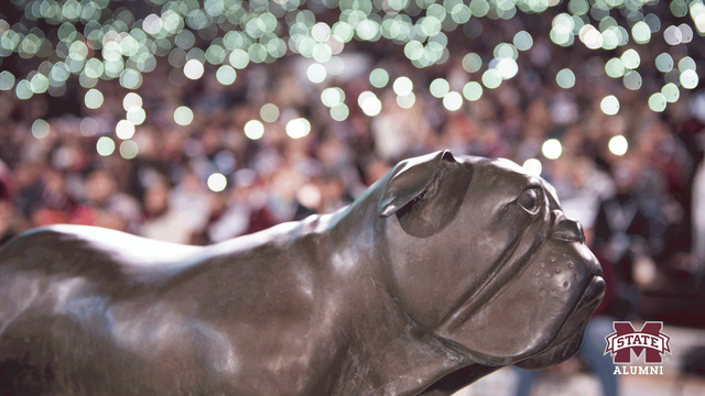 Picture of Bully statue in front of blurred out lights on a maroon background